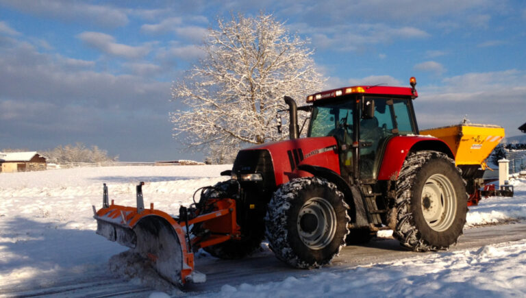 Tracteur de déneigement devant une route enneigée
